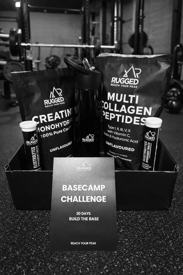 Rugged supplement packages and 'Basecamp Challenge' sign in a gym setting